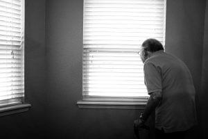 Opa in Einsamkeit mit Blick aus dem Fenster