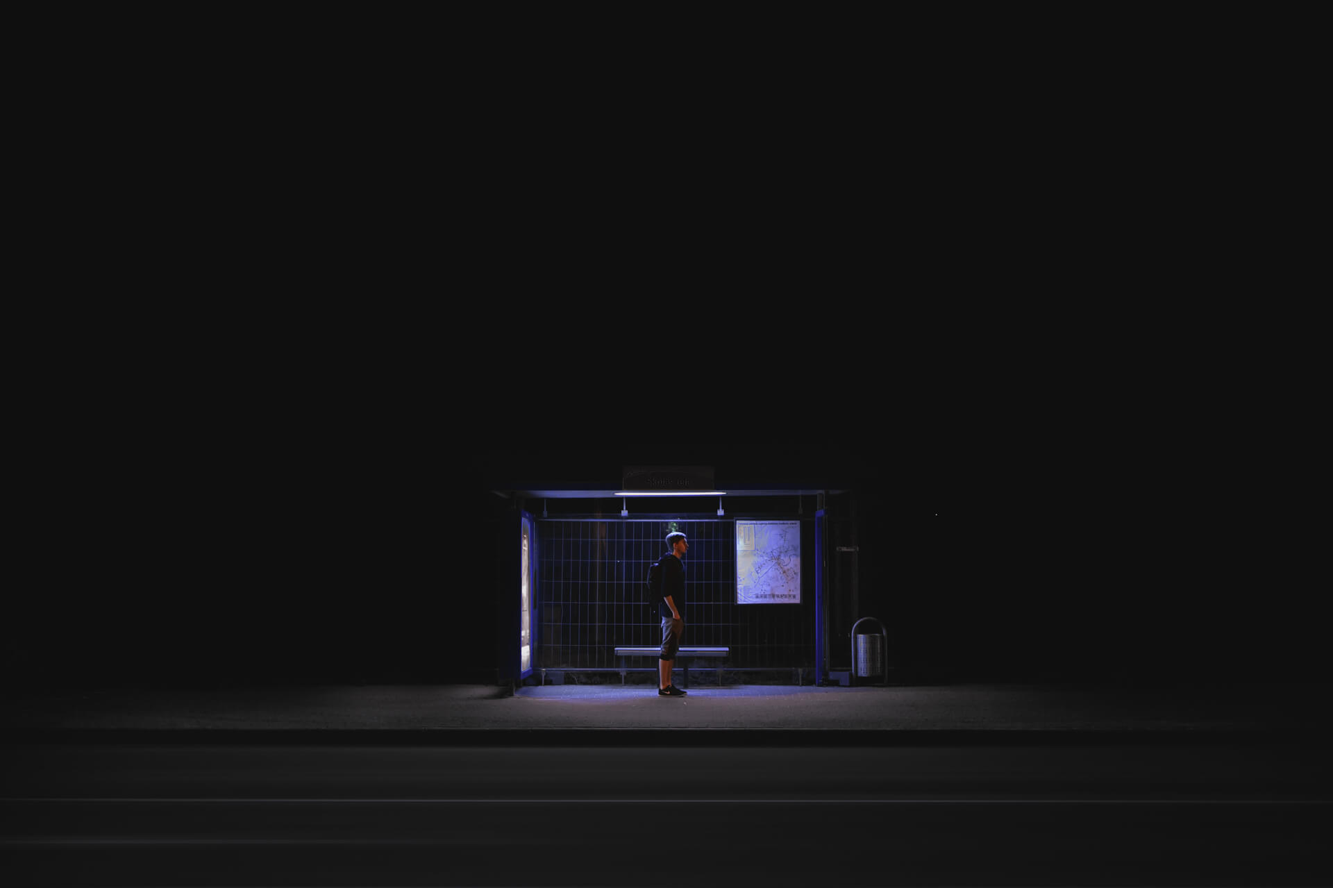 Individuum alleine an Bushaltestelle in der Nacht